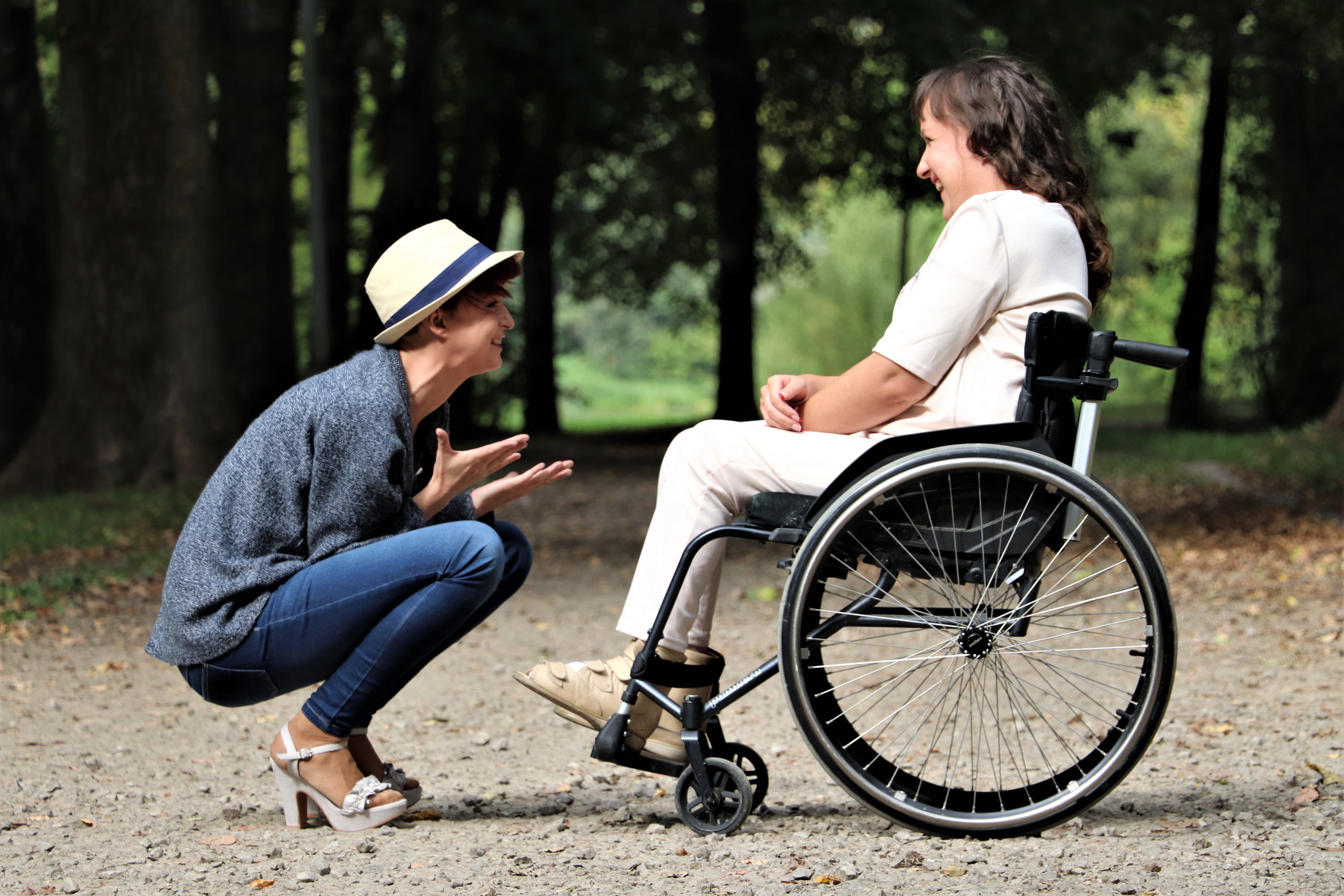 En person på huk mittemot en person i rullstol 