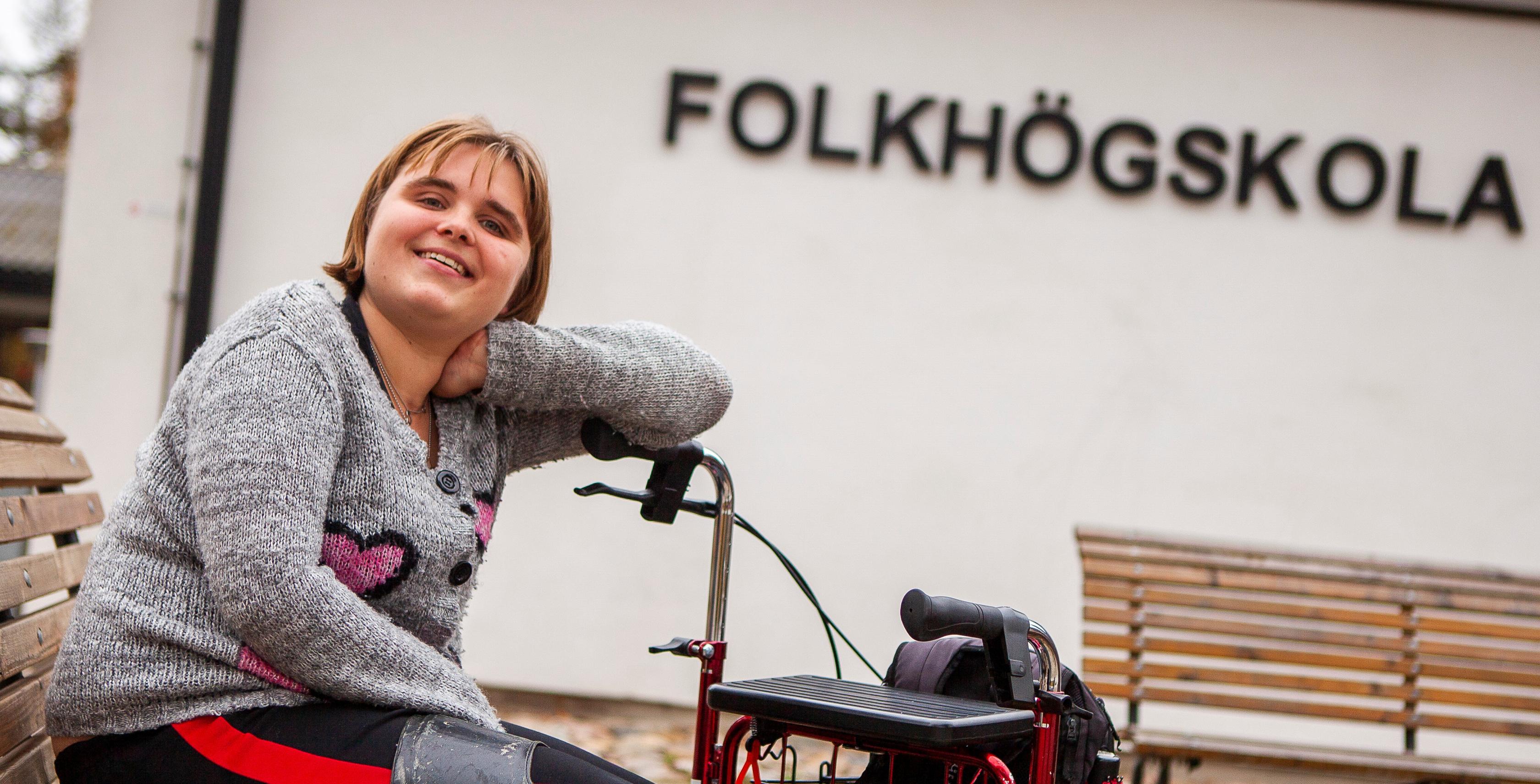 Tjej sitter på en permobil och ler in i kameran
