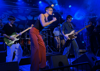 En man sjunger på scen framför andra musiker