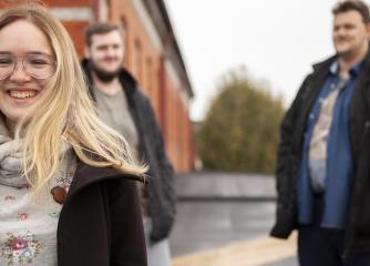 En leende kvinna och i bakgrunden två män