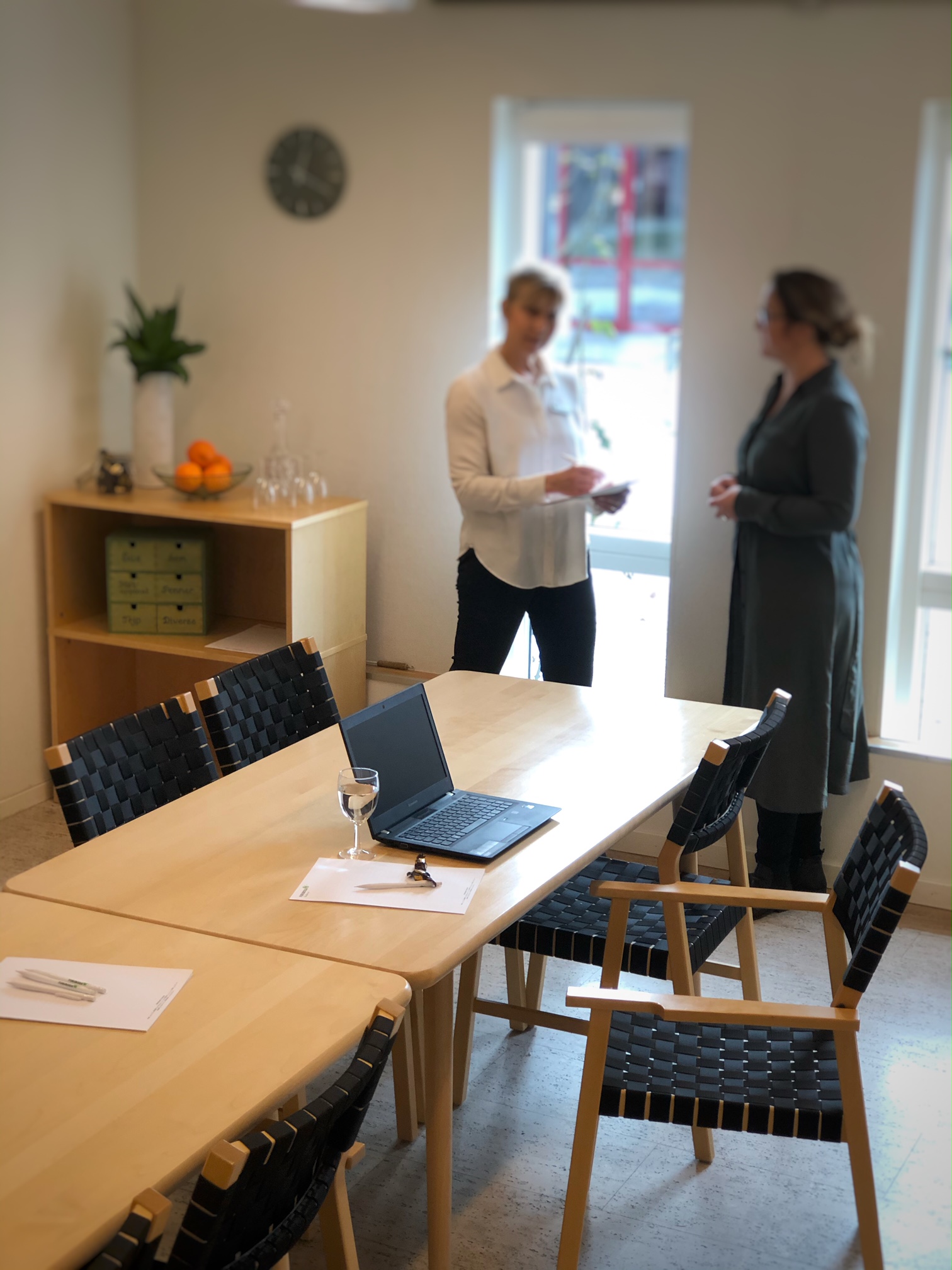 Ett konferensbord och i bakgrunden står två personer