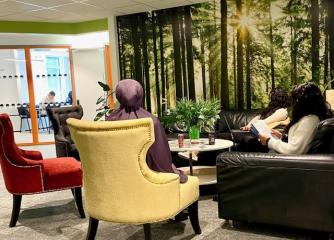 Tre kvinnor som sitter i soffor och fåtölj med en bild av träd i bakgrunden